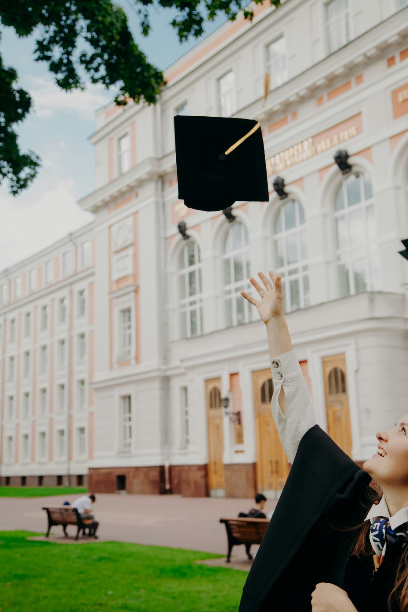Étudiante en toge lançant sa toque de diplômée devant une université européenne